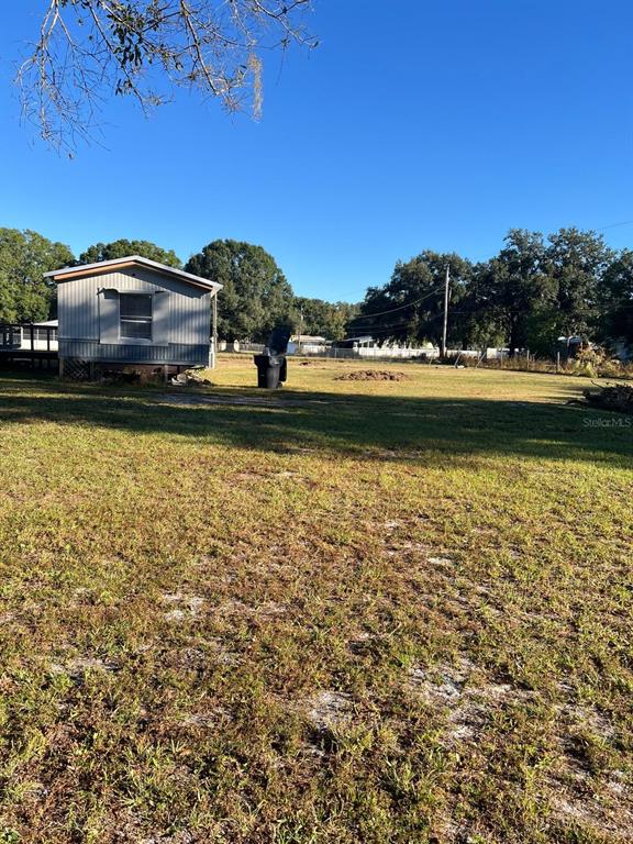 A mobile home sits on a large, grassy lot under a clear blue sky — 4015 SHADY OAK DRIVE E, LAKELAND, FL