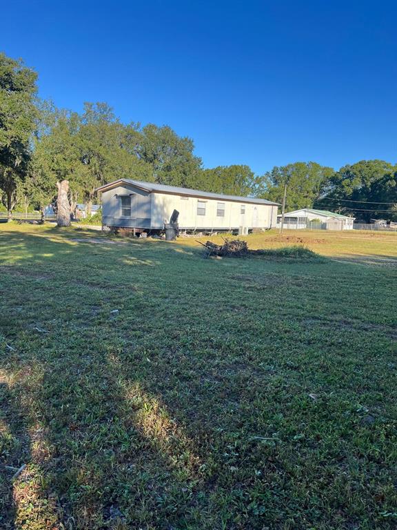 A single-story manufactured home sits on a grassy lot under a clear blue sky — 4015 SHADY OAK DRIVE E, LAKELAND, FL