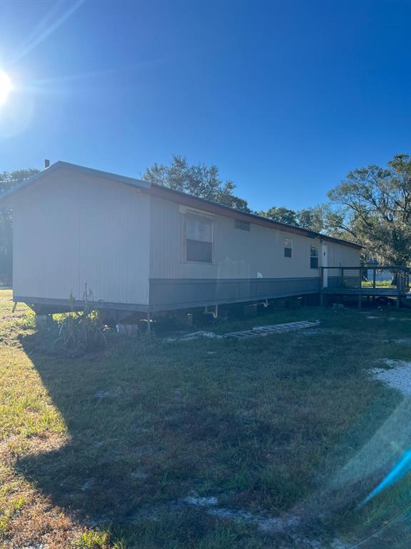 A single-story manufactured home with light siding sits on a grassy lot under a clear sky — 4015 SHADY OAK DRIVE E, LAKELAND, FL