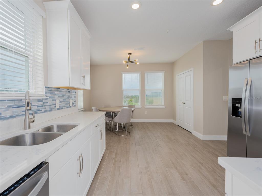 A kitchen with white cabinets, stainless steel appliances, and a dining area with light flooring — 7517 LAUREATE BOULEVARD UNIT 4303, ORLANDO, FL