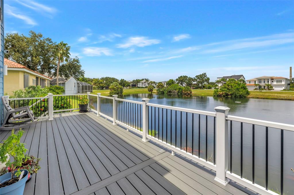 A gray composite deck with white railings overlooks a pond surrounded by houses and trees — 2111 HARBOUR WATCH DRIVE, TARPON SPRINGS, FL