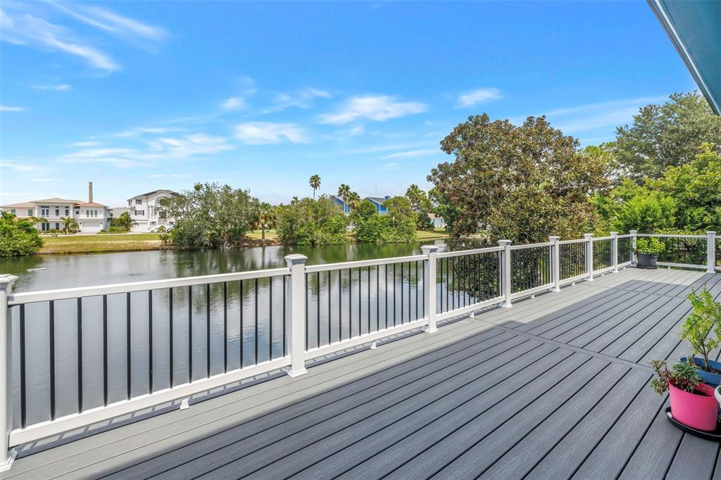 A gray composite deck features a white railing overlooking a calm canal and residential homes — 2111 HARBOUR WATCH DRIVE, TARPON SPRINGS, FL