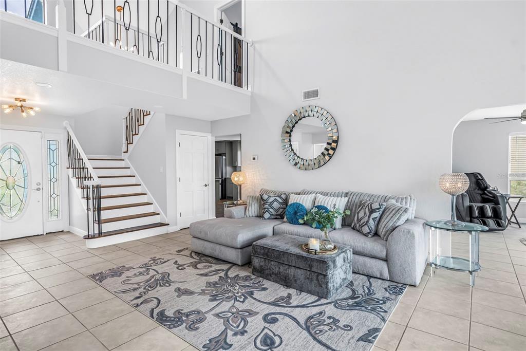 A living room features a sectional sofa, a patterned area rug, and a staircase — 2111 HARBOUR WATCH DRIVE, TARPON SPRINGS, FL