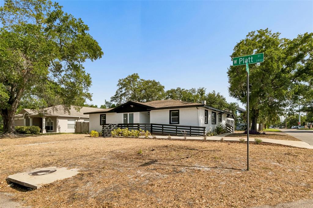 A white single-story house with a black roof and porch railing sits on a corner lot — 3901 W PLATT STREET W UNIT 12, TAMPA, FL