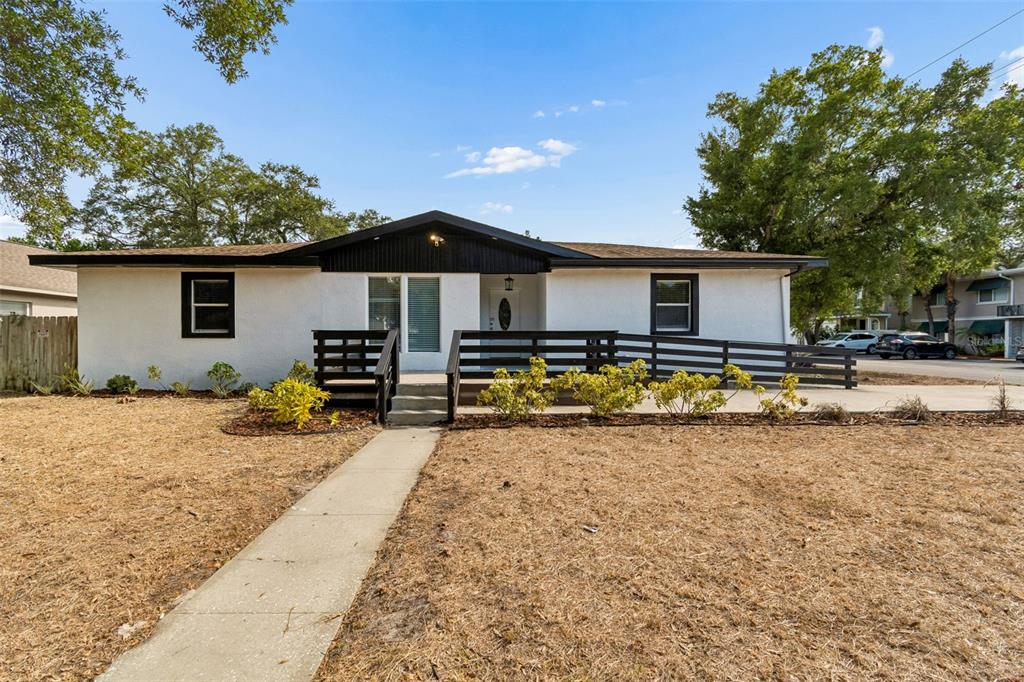A single-story house with a white stucco exterior, black trim, and a front wooden deck — 3901 W PLATT STREET W UNIT 12, TAMPA, FL
