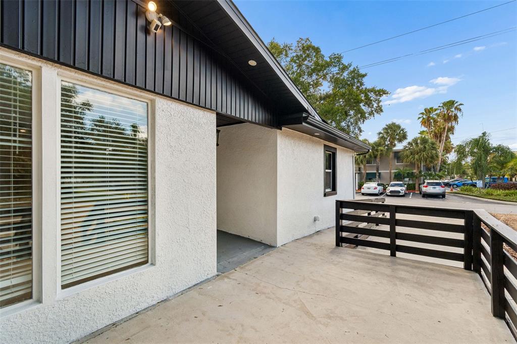 A concrete patio with a black wooden railing sits outside a white stucco building — 3901 W PLATT STREET W UNIT 12, TAMPA, FL