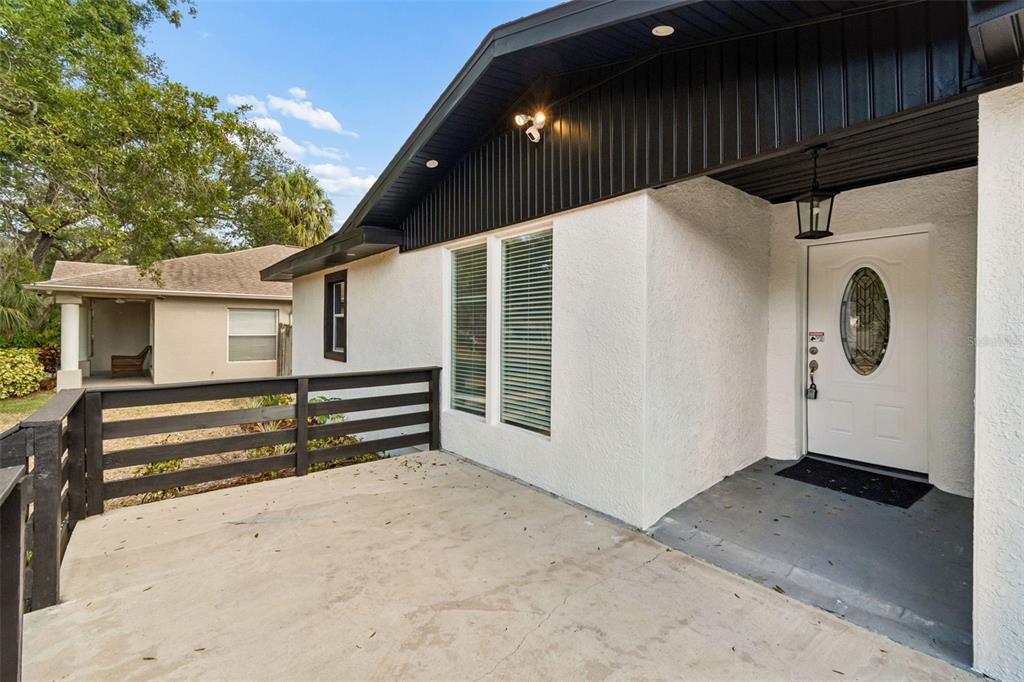 A white stucco house exterior features a black-railed concrete porch and a white front door — 3901 W PLATT STREET W UNIT 12, TAMPA, FL