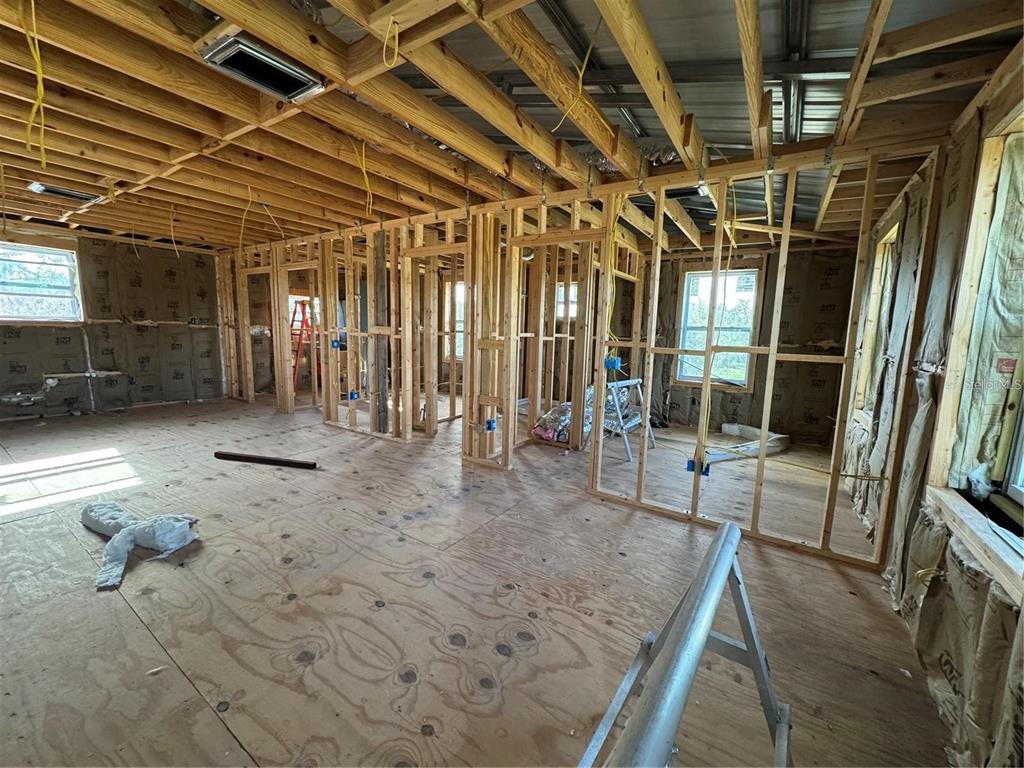 An unfinished room under construction with exposed wooden wall studs, ceiling joists, and plywood flooring — 206 BRANDYWINE TRAIL, FROSTPROOF, FL