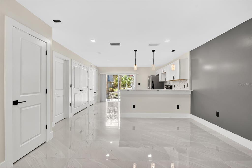 A bright room features white tile flooring, a kitchen with a breakfast bar, and sliding doors — 7300 DANIEL WEBSTER DRIVE UNIT M7, WINTER PARK, FL