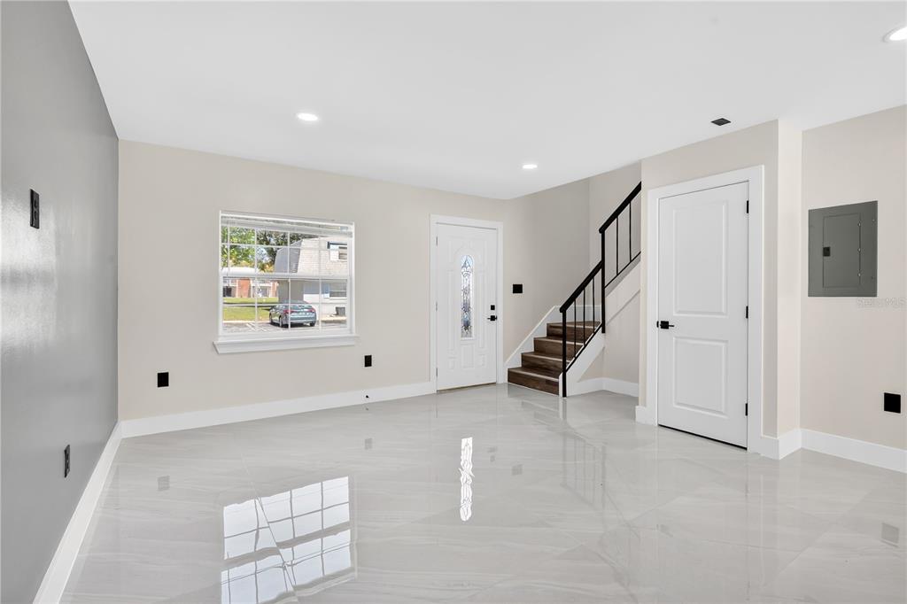A bright room with light-colored tile flooring, a staircase, a front door, and a window — 7300 DANIEL WEBSTER DRIVE UNIT M7, WINTER PARK, FL