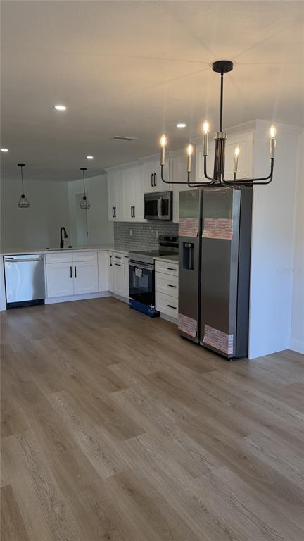 A dining area features light wood-look flooring, white walls, and a black six-light chandelier — 1421 HEATHER DRIVE, DUNEDIN, FL