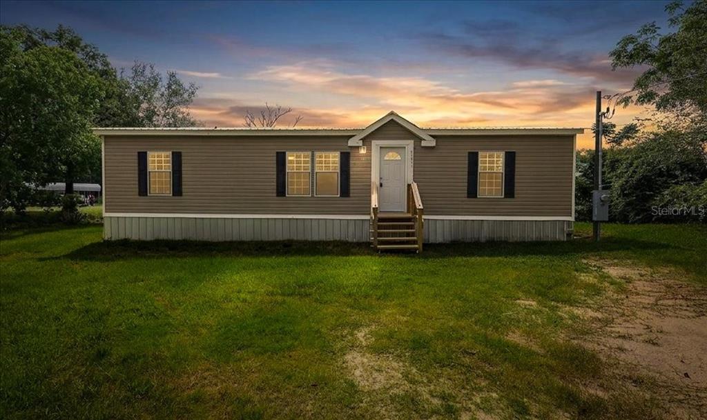 An aerial view shows a house with a metal roof near a lake and dock — 8581 NE 147TH COURT, SILVER SPRINGS, FL