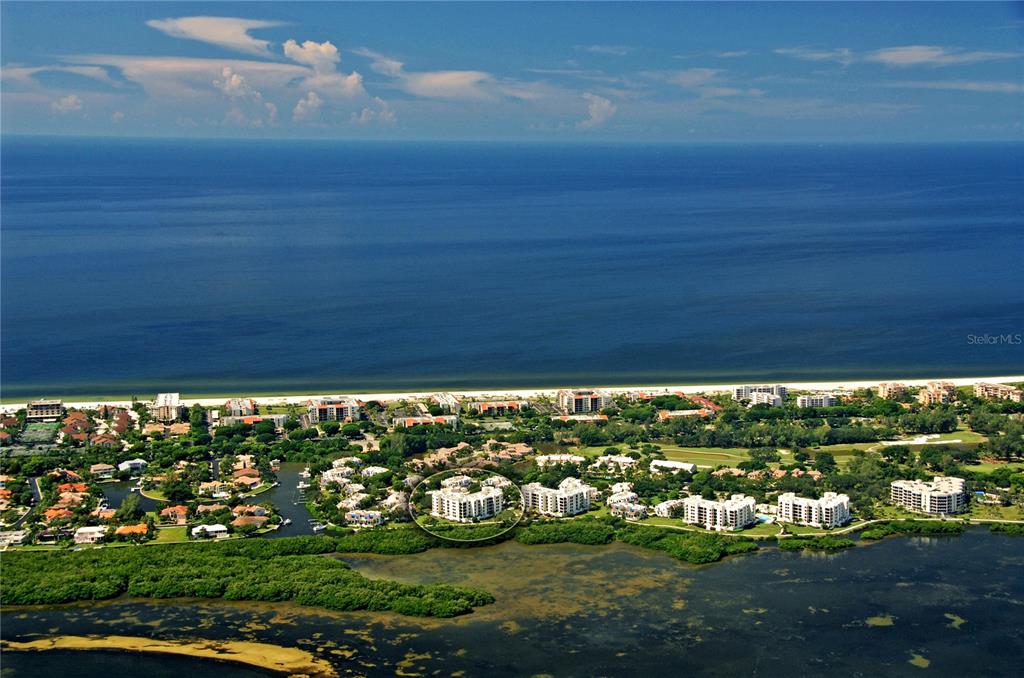An aerial view shows a coastal residential complex with a circled building near the water — 1930 HARBOURSIDE DRIVE UNIT 122, LONGBOAT KEY, FL