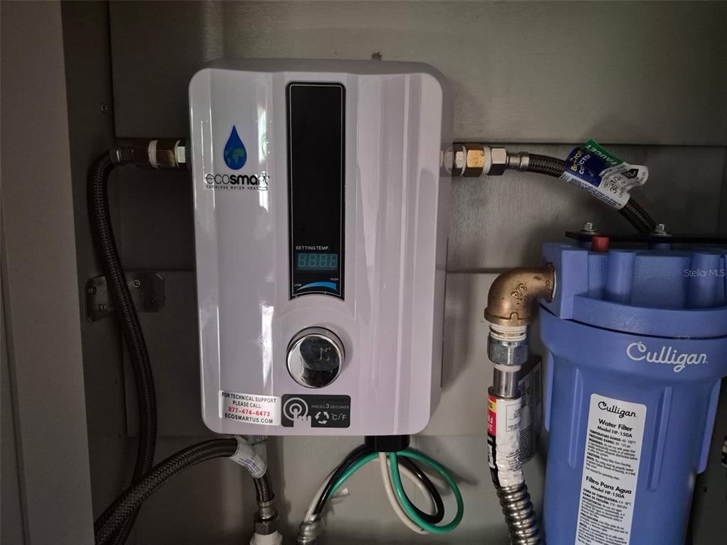 An Ecosmart tankless water heater and a Culligan water filter are mounted inside a cabinet — 15764 NE 235TH PLACE, FORT MC COY, FL