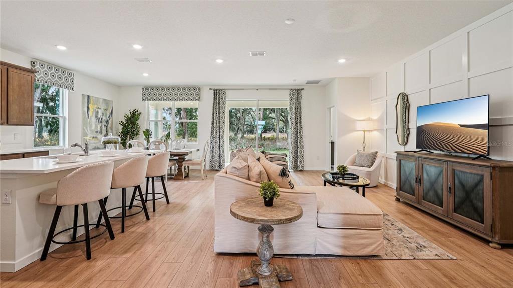 An open-concept living area features a kitchen island, a sectional sofa, and a television console — 4555 NW 39TH STREET ROAD, OCALA, FL