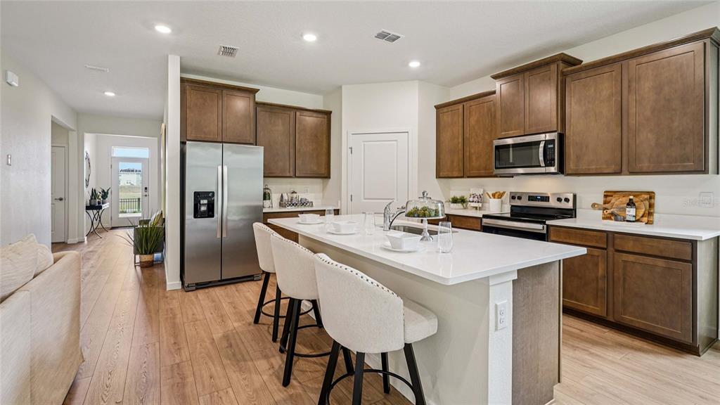 A modern kitchen features dark wood cabinets, white countertops, a central island, and stainless appliances — 4555 NW 39TH STREET ROAD, OCALA, FL
