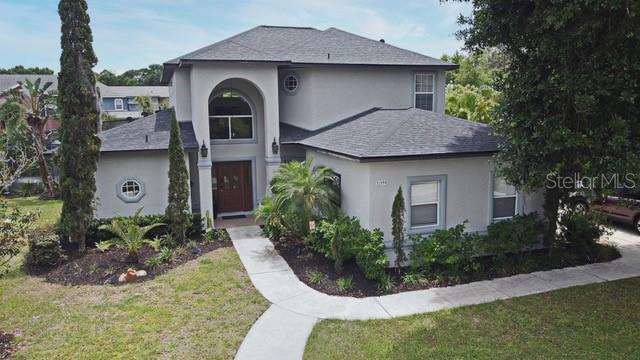 A two-story house with a gray exterior, arched entryway, and a concrete walkway — 11994 MCKINNON ROAD, WINDERMERE, FL