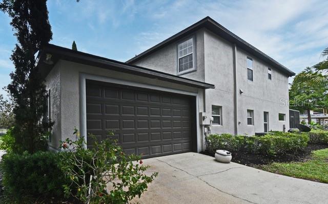 A two-story house exterior features a dark brown garage door and light-colored stucco siding — 11994 MCKINNON ROAD, WINDERMERE, FL