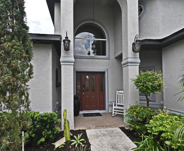 The exterior of a home features a covered entryway with columns and a wooden door — 11994 MCKINNON ROAD, WINDERMERE, FL