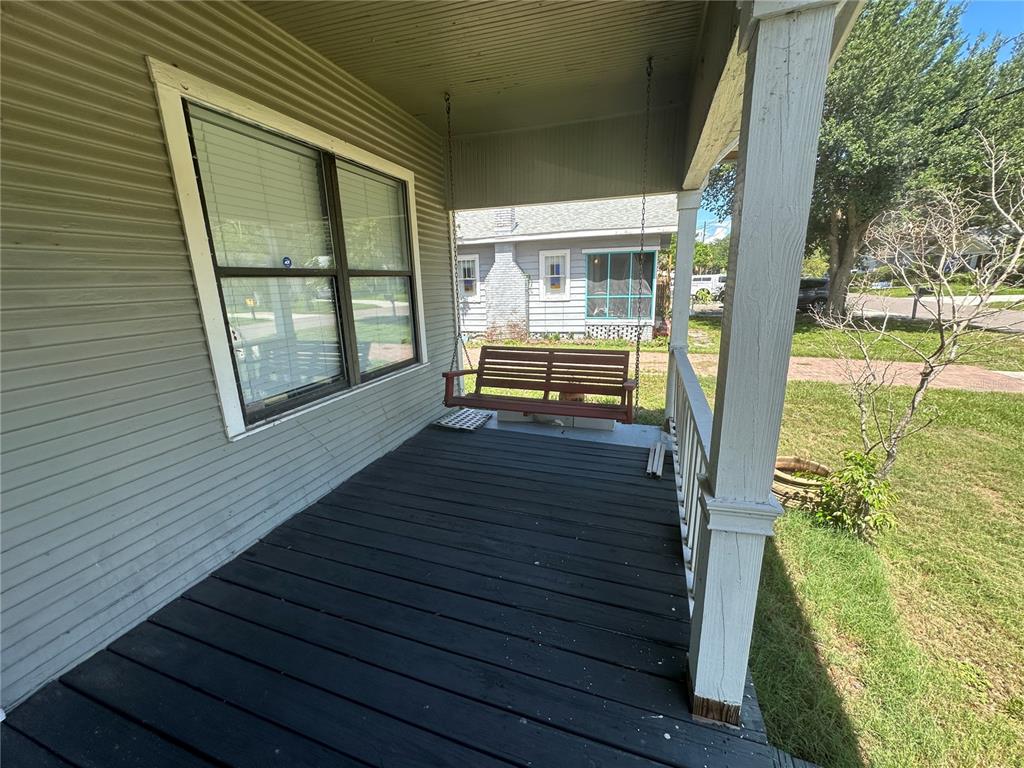 A covered front porch features dark wooden decking, a hanging swing, and white railings — 1308 E FRIERSON AVENUE, TAMPA, FL