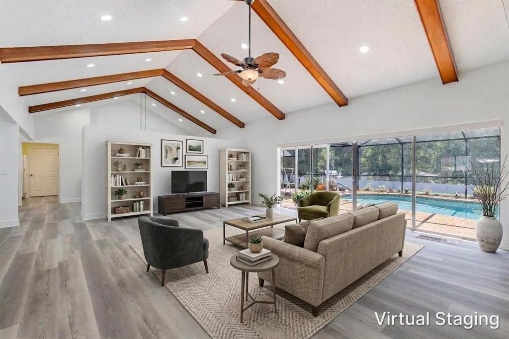 A living room with vaulted ceilings, exposed wood beams, and a view of a pool — 33816 SPRING DRIVE, LEESBURG, FL
