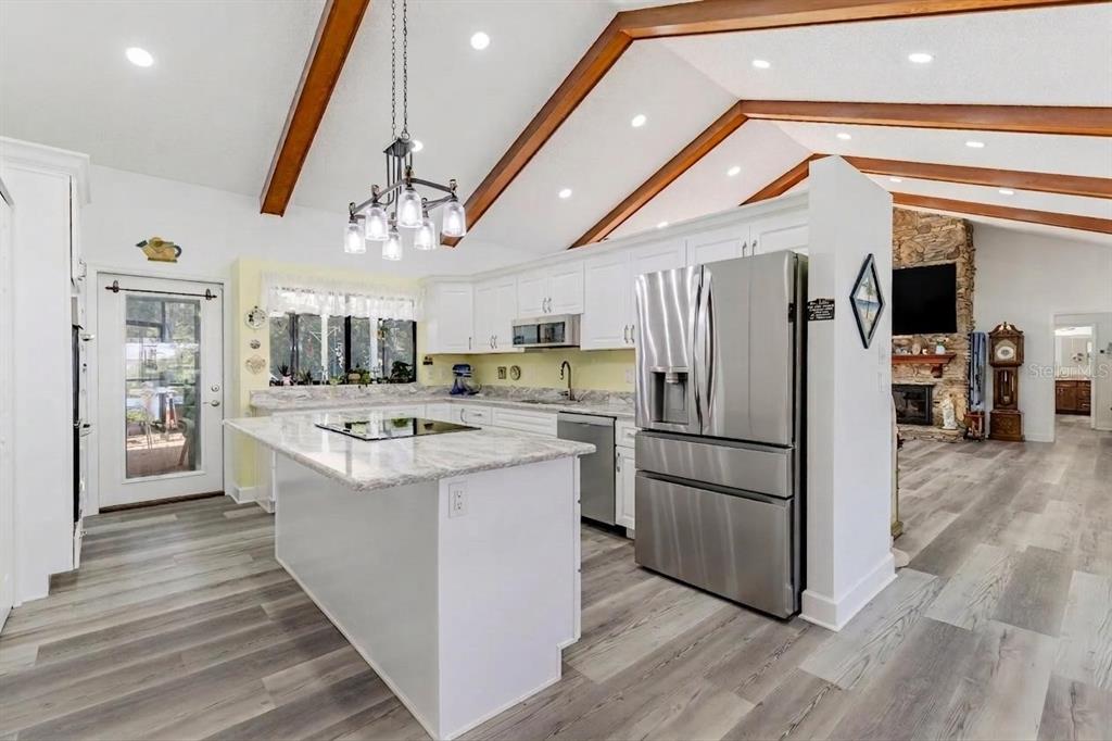 A kitchen with white cabinets, granite countertops, a center island, and vaulted ceilings with beams — 33816 SPRING DRIVE, LEESBURG, FL