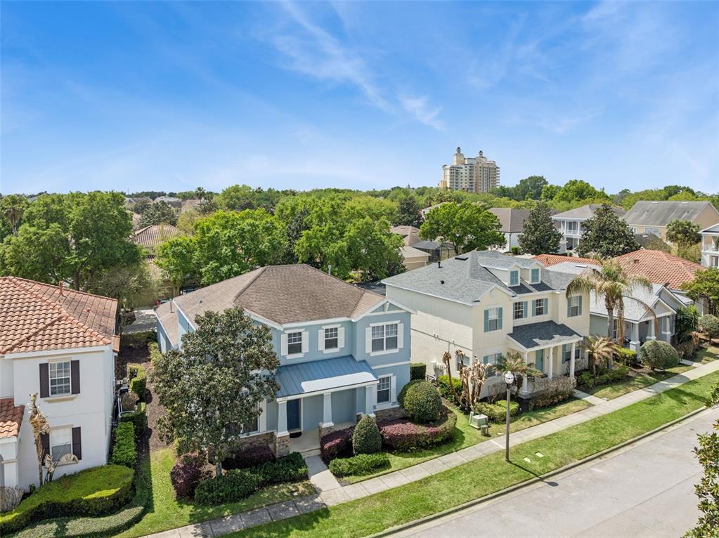 An aerial view shows several suburban houses with landscaped yards and trees under a blue sky — 7412 DEVEREAUX STREET, REUNION, FL
