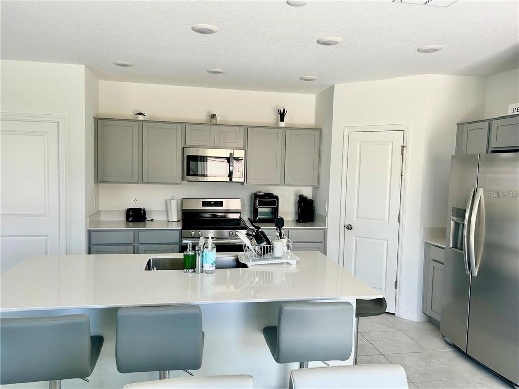 A kitchen features gray cabinets, stainless steel appliances, a white island, and recessed lighting — 572 REGGIE ROAD, WINTER HAVEN, FL
