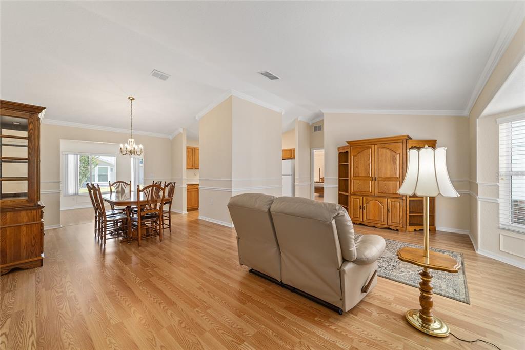A living and dining area features light wood flooring, beige walls, and traditional wooden furniture — 11283 SW 139TH PLACE, DUNNELLON, FL