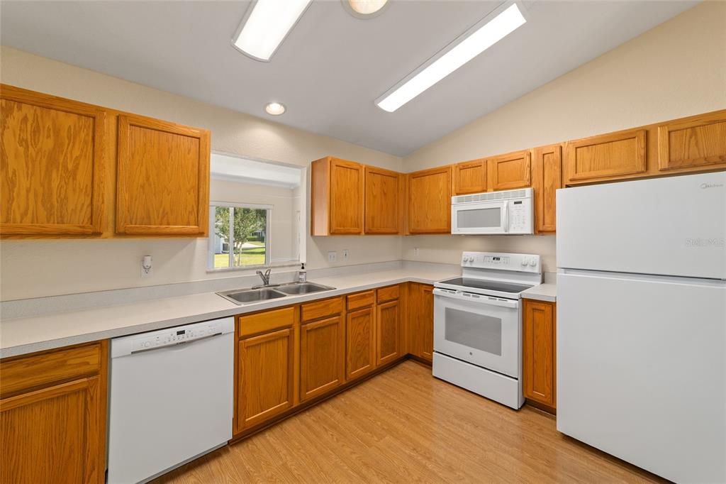 A kitchen featuring wood cabinets, white appliances, laminate countertops, and light wood-look flooring — 11283 SW 139TH PLACE, DUNNELLON, FL