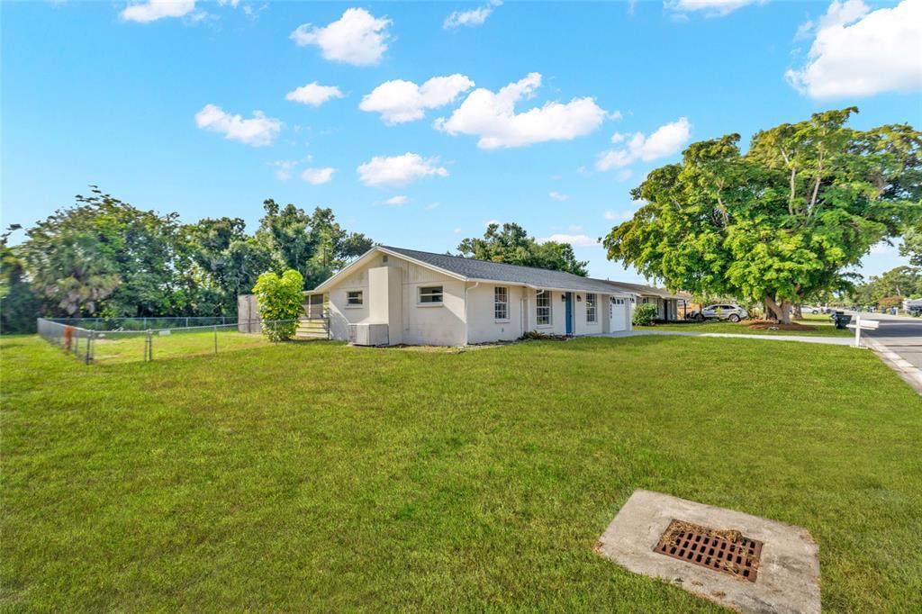 A single-story house with a white exterior sits on a large, grassy corner lot — 4603 ATLANTIC AVENUE, SARASOTA, FL