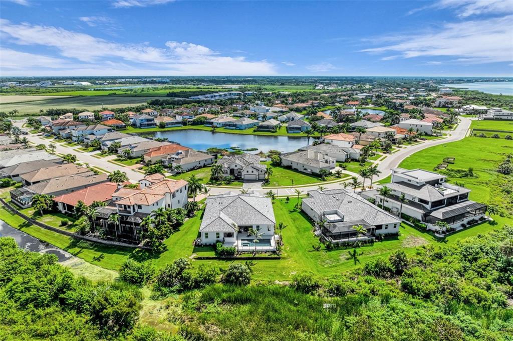 An aerial view of a suburban neighborhood featuring houses surrounding a central pond — 6264 CHAMPIONS ROW STREET, BRADENTON, FL
