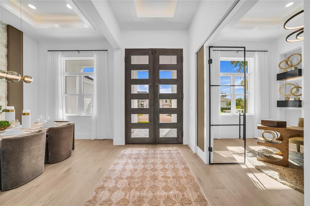 A bright entryway features light wood floors, a patterned rug, and dark double front doors — 6264 CHAMPIONS ROW STREET, BRADENTON, FL