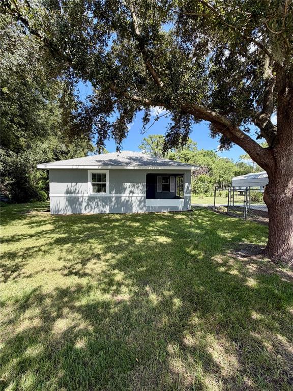 A gray single-story house with a covered porch sits on a grassy lot under trees — 214 KING ROAD, WINTER HAVEN, FL
