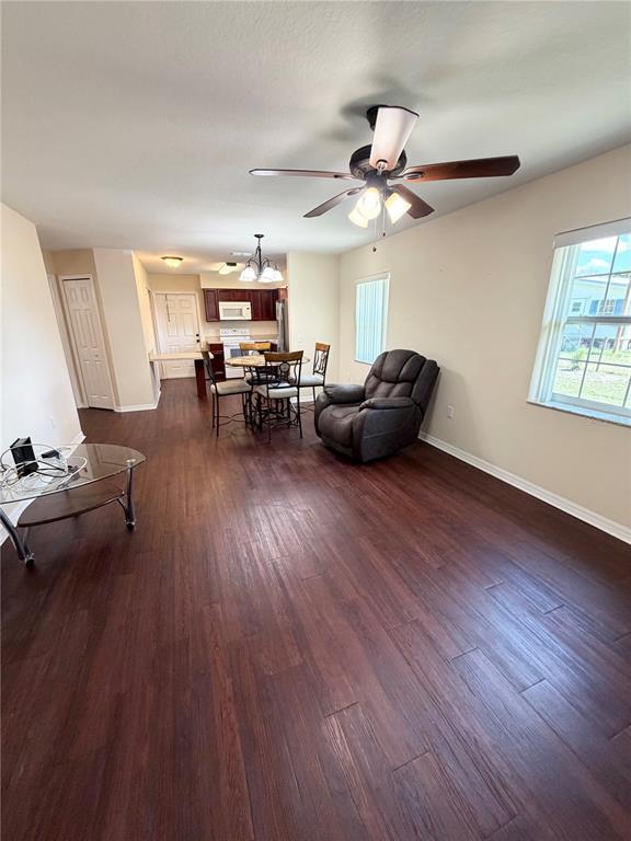 An open-concept living and dining area features dark wood-look flooring and a ceiling fan — 214 KING ROAD, WINTER HAVEN, FL