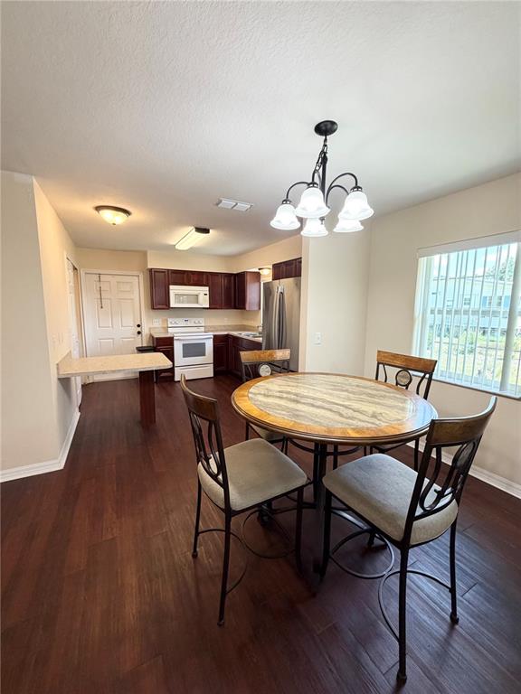 A dining area with a round table and chairs sits adjacent to a kitchen with dark cabinets — 214 KING ROAD, WINTER HAVEN, FL