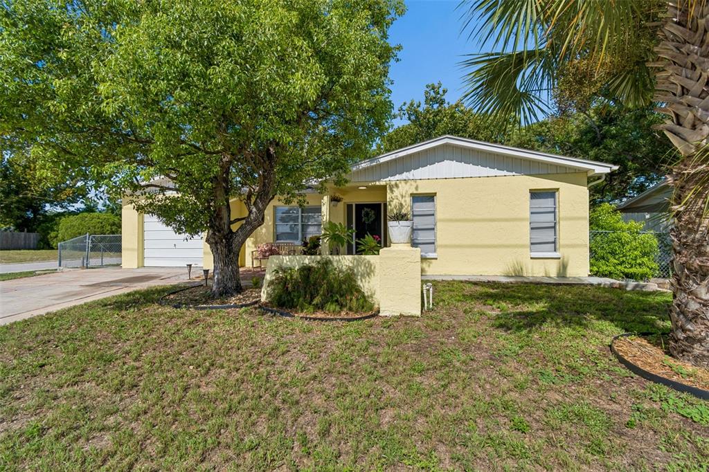 A single-story yellow house with a garage, a large tree, and a front yard — 9631 MARLINTON LANE, PORT RICHEY, FL