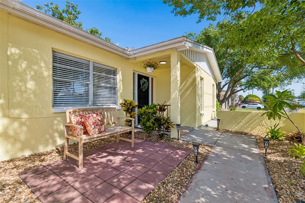 A yellow house exterior features a front porch with a bench and a concrete walkway — 9631 MARLINTON LANE, PORT RICHEY, FL