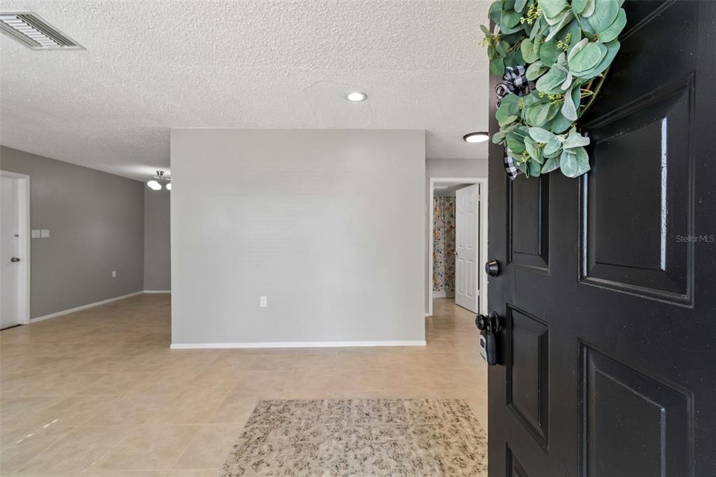 An entryway opens into a living area with light gray walls and beige tile flooring — 9631 MARLINTON LANE, PORT RICHEY, FL