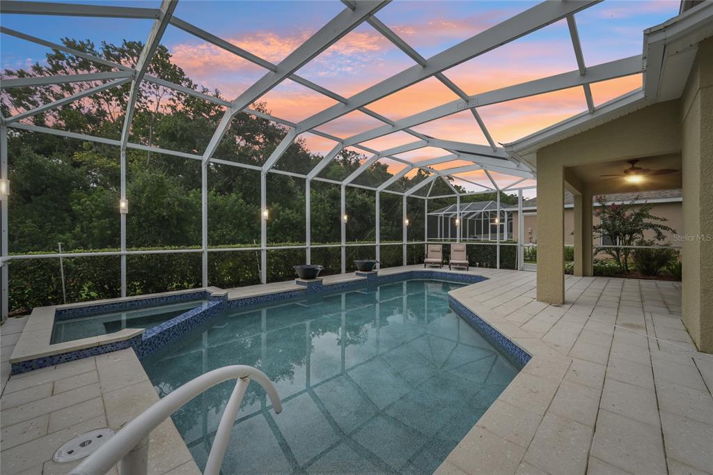 A screened-in swimming pool and spa area with a covered patio at sunset — 8124 115TH AVENUE E, PARRISH, FL