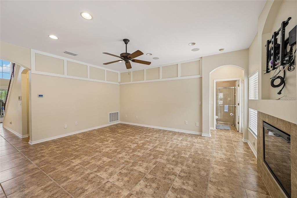 A spacious living room features tile flooring, a ceiling fan, and a fireplace — 8124 115TH AVENUE E, PARRISH, FL