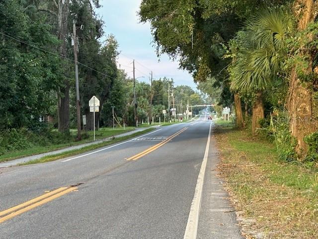 A vacant, grassy residential lot features several mature trees under a blue sky — SW 4TH AVE., CHIEFLAND, FL