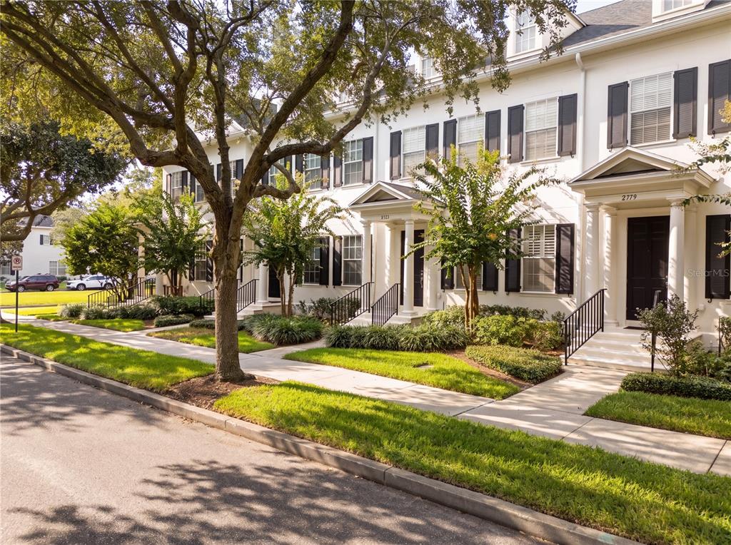 A row of white townhouses with black shutters and front porches lines a sidewalk — 2783 UPPER PARK ROAD, ORLANDO, FL
