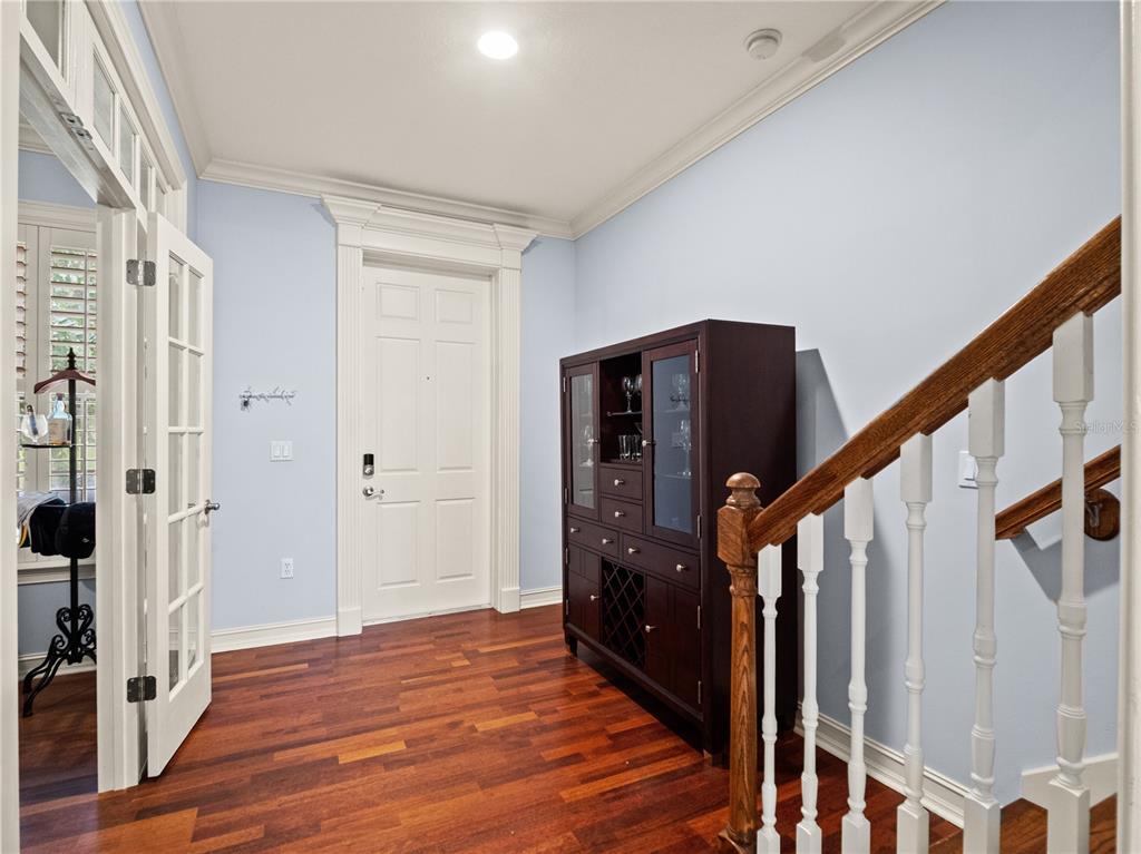 A foyer features light blue walls, hardwood floors, a dark wood cabinet, and a staircase — 2783 UPPER PARK ROAD, ORLANDO, FL