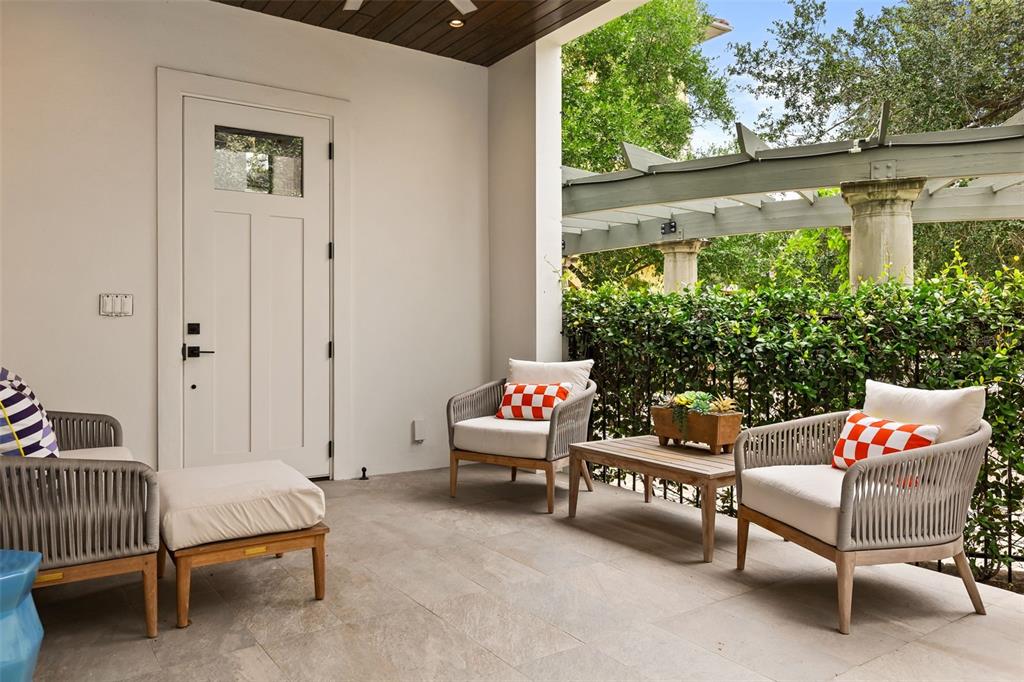 A covered patio features a stone fire pit table, Adirondack chairs, and a wood-paneled ceiling — 660 W MORSE BOULEVARD, WINTER PARK, FL