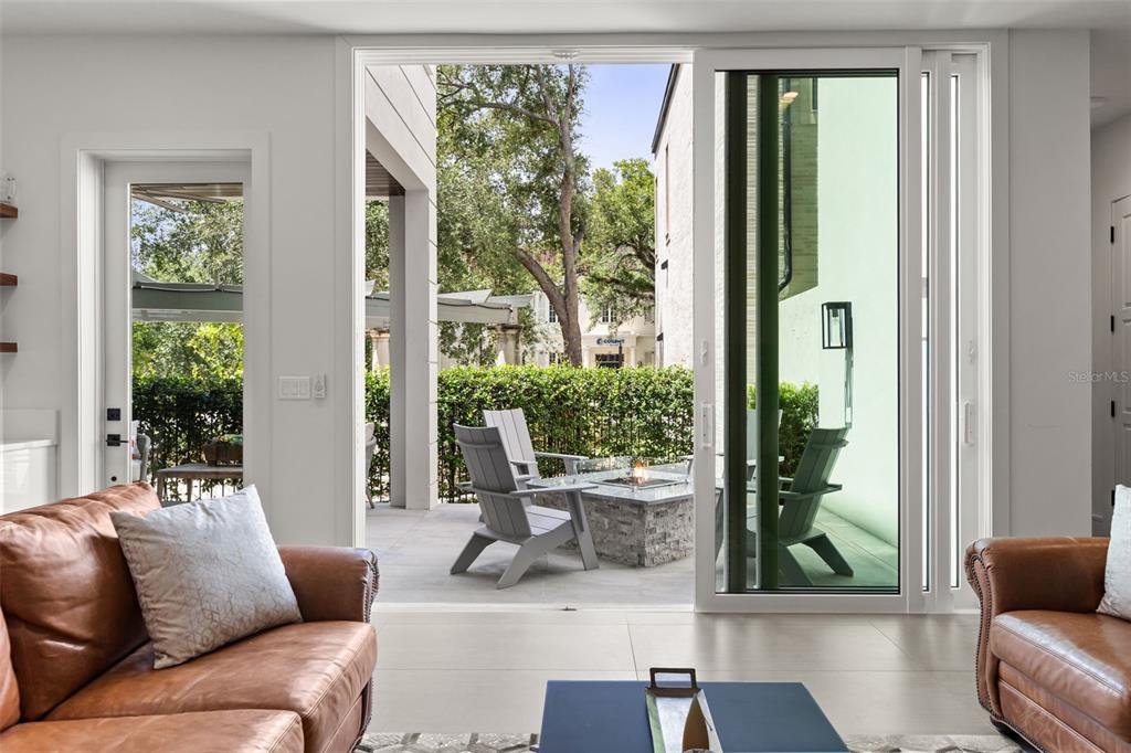 A covered patio features stone flooring, three armchairs with cushions, a coffee table, and a door — 660 W MORSE BOULEVARD, WINTER PARK, FL