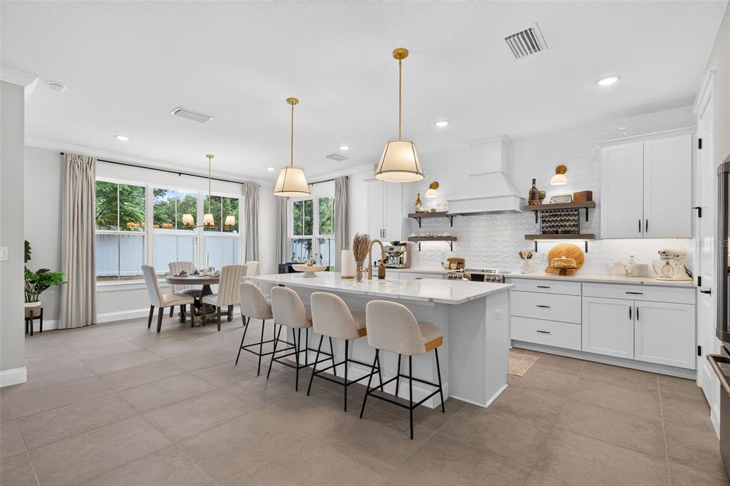 A modern kitchen features a large white island, bar seating, and light-colored cabinetry — 231 SEVERN WAY, ORLANDO, FL
