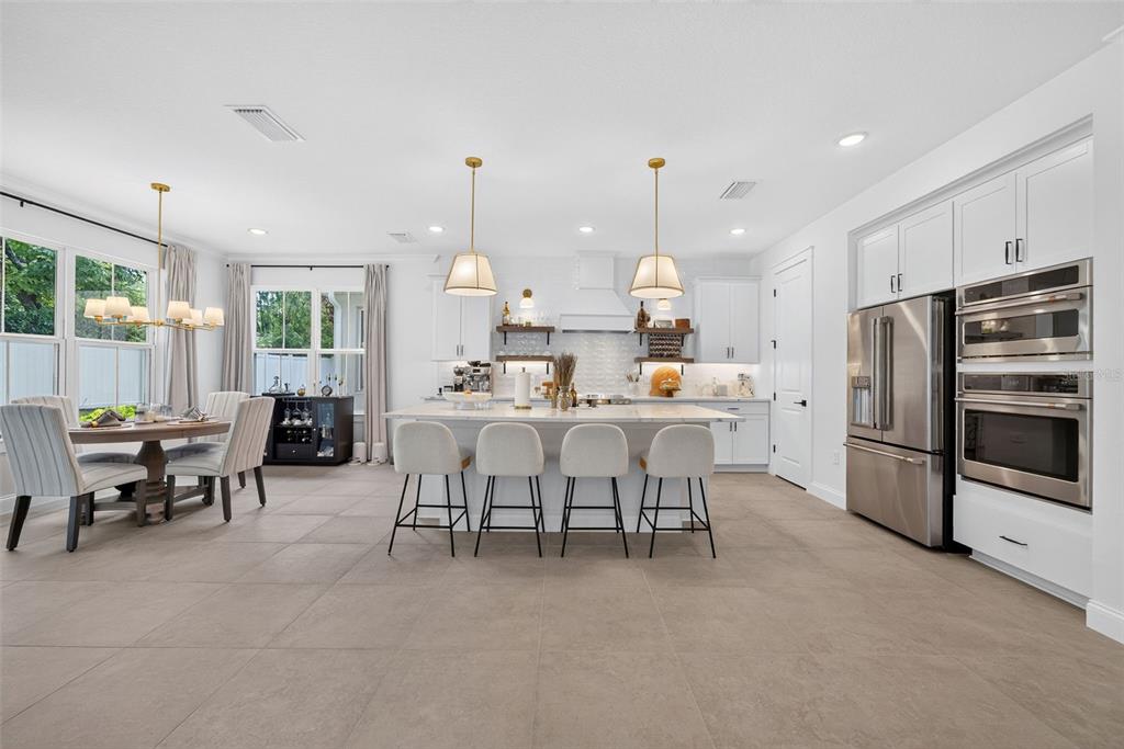A modern kitchen features a large marble island, white cabinetry, stainless steel appliances, and tile flooring — 231 SEVERN WAY, ORLANDO, FL