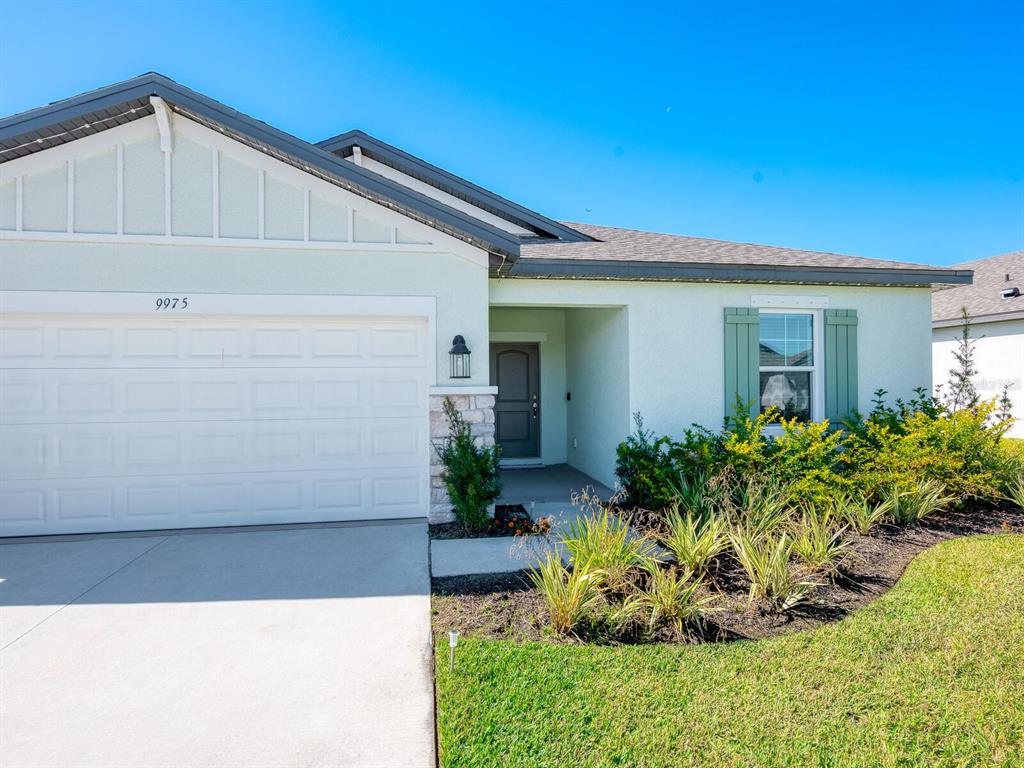 A single-story house with a white garage, stone accents, and green shutters on the window — 9975 LAST LIGHT GLEN, PARRISH, FL