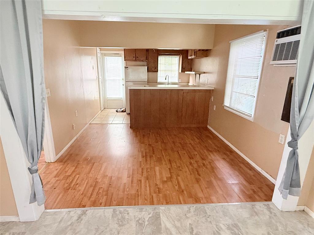 A room with wood-look flooring, a large window with blinds, and a doorway to outside — 1661 27TH AVENUE N, ST PETERSBURG, FL